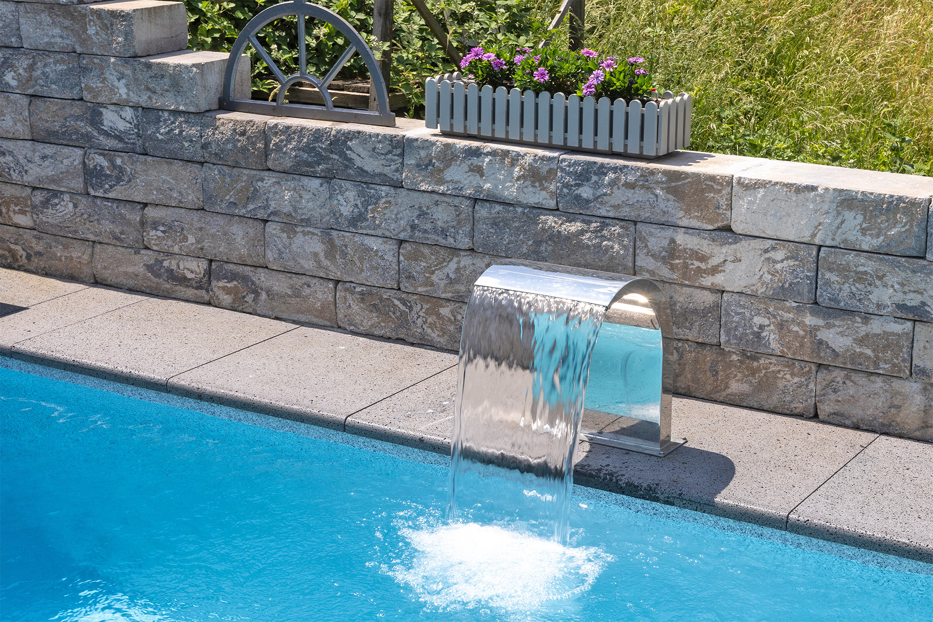 Wasserstrahl am Pool mit Natursteinumrandung