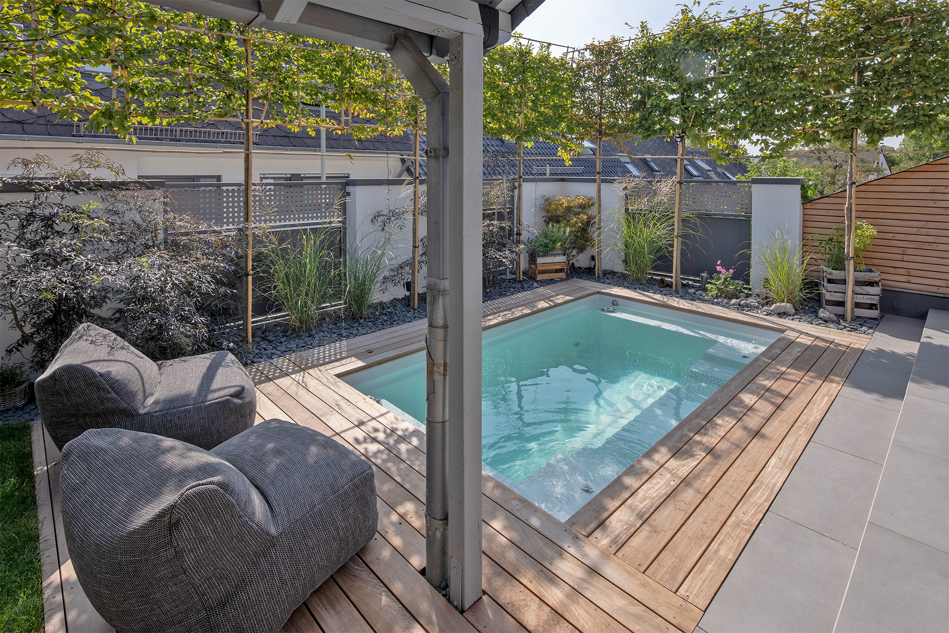 Heller Swimmingpool mit Spalierbäumen als Sichtschutz